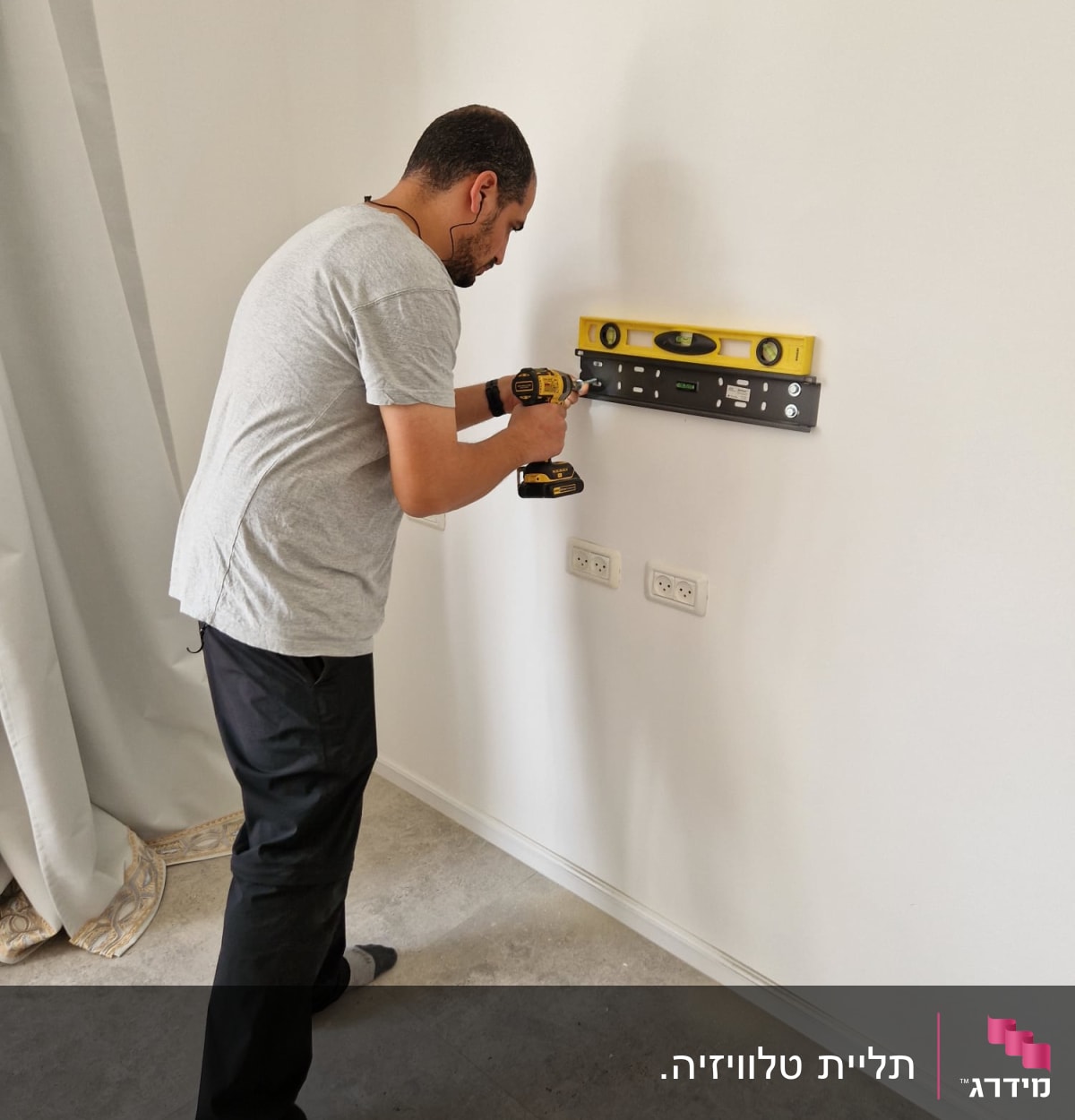 אדם משתמש במקדחה ומפלס על קיר לבן